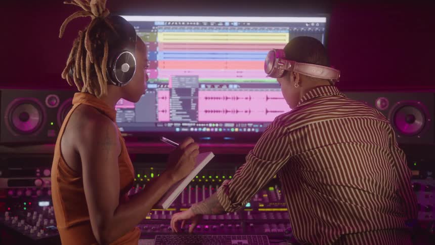 Music production in a studio with two professionals adjusting recordings on the mixing console