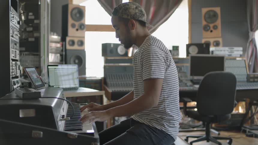 A man plays the keyboard in a music recording studio