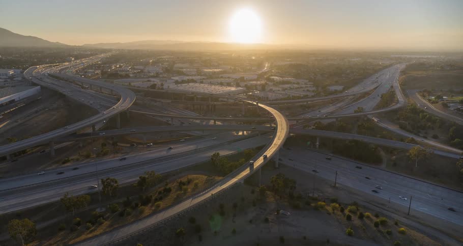 An aerial view of highway interchange at sunset with light traffic on the roads