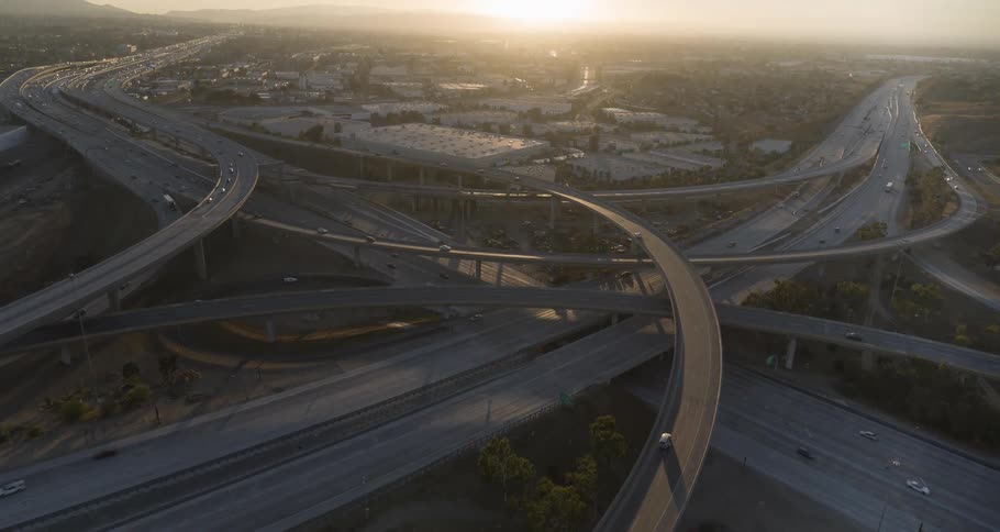 Aerial view of a large highway interchange at sunset with vehicles in motion