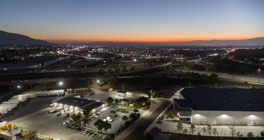 Aerial of a car park and building beside busy freeways and overpasses in a metropolitan city at night