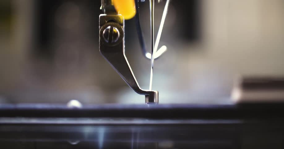 A macro shot of a sewing machine needle stitching fabric