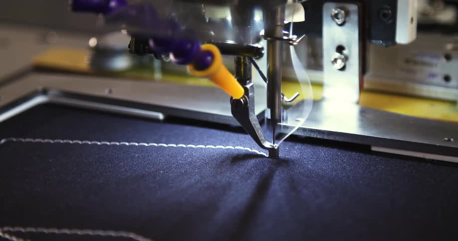 A computerized sewing machine creates a neat rectangular border on dark fabric