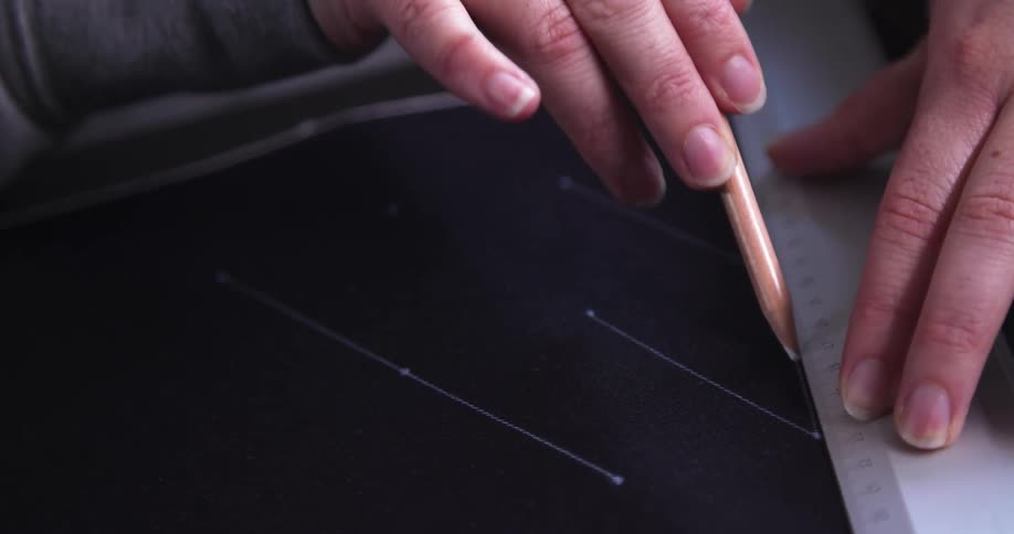 Designer precisely measures and marks fabric with pencil and ruler