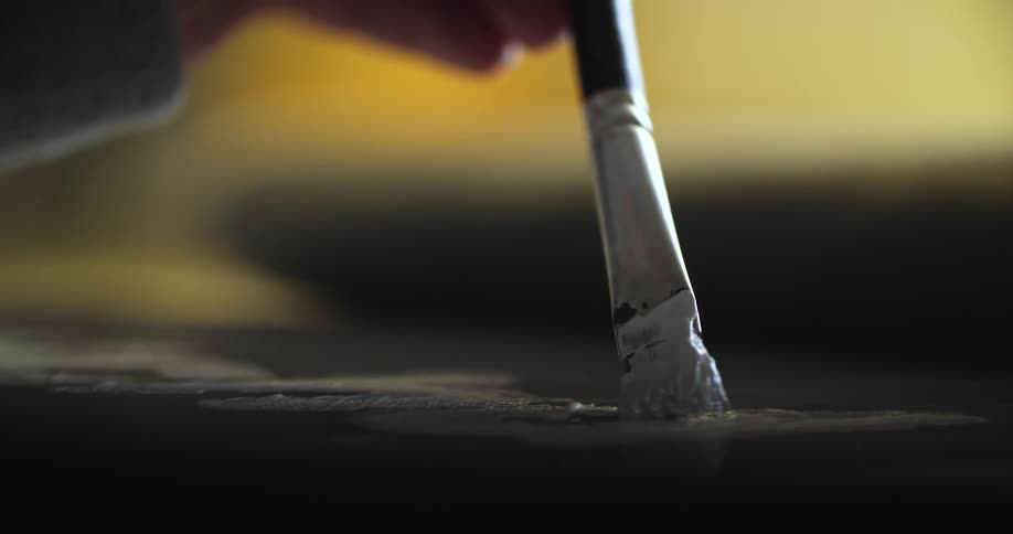 The artist is using white paint with a small brush