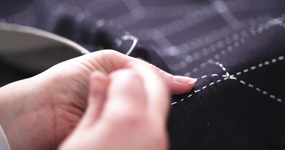 Woman sewing a piece of fabric by hand using a needle and thread
