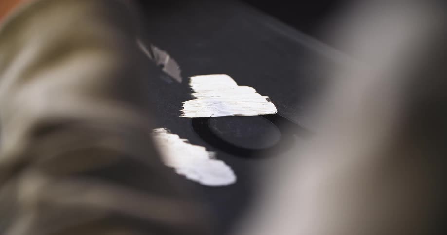 Woman spreading paint on top of a table at midday
