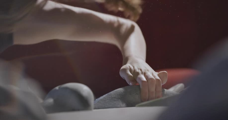A low angle close view shows a womans rock climbing in an indoor gym