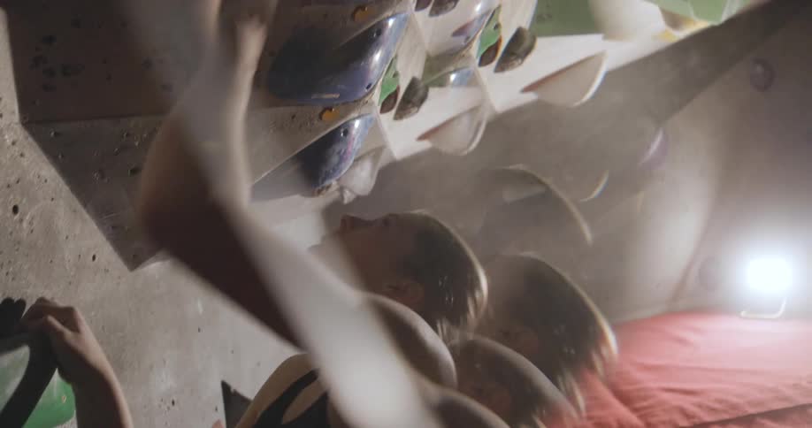 A person climbs an overhanging indoor bouldering wall with determination