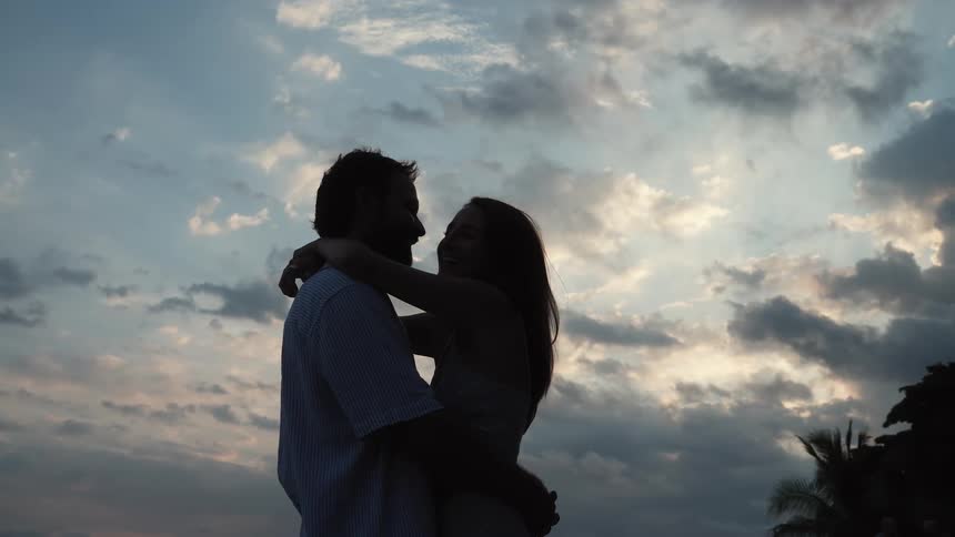 Close up of a young couple hugging each other romantically while standing outdoors during daytime