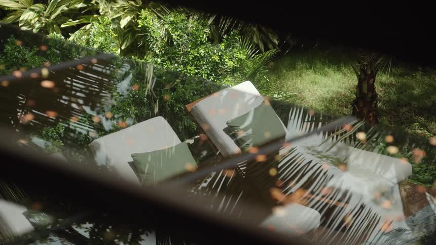 The shadows of palm fronds move across outdoor furniture in a garden as the sun shifts