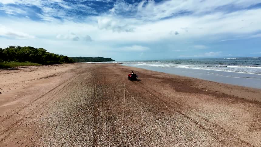 A person rides a quad bike buggy over the beach