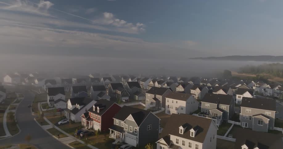 School bus drives through a coastal residential neighborhood on a foggy day
