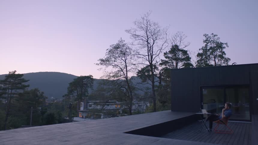 A man sits on a porch at sunset