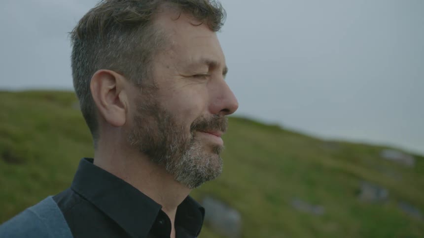 A man looks from side to side in a valley smiling