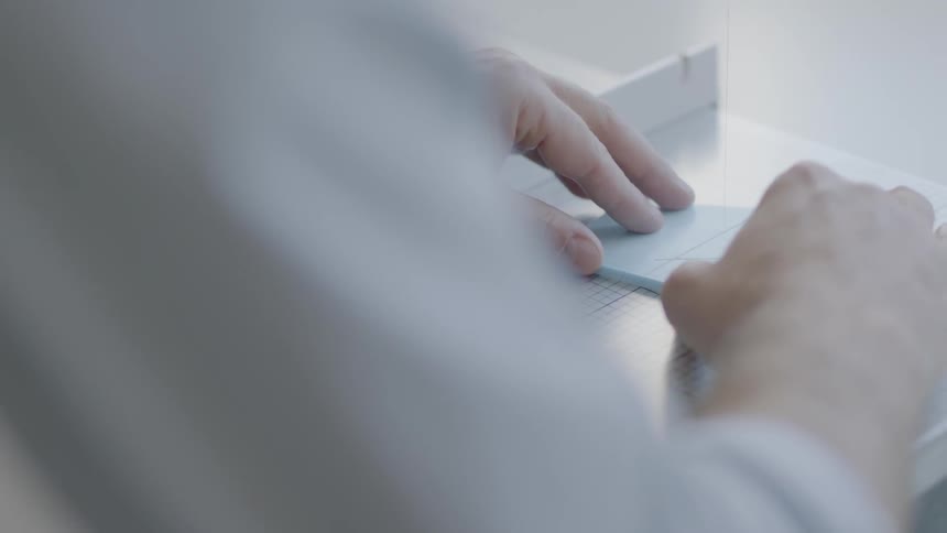 A man is measuring something on a desk