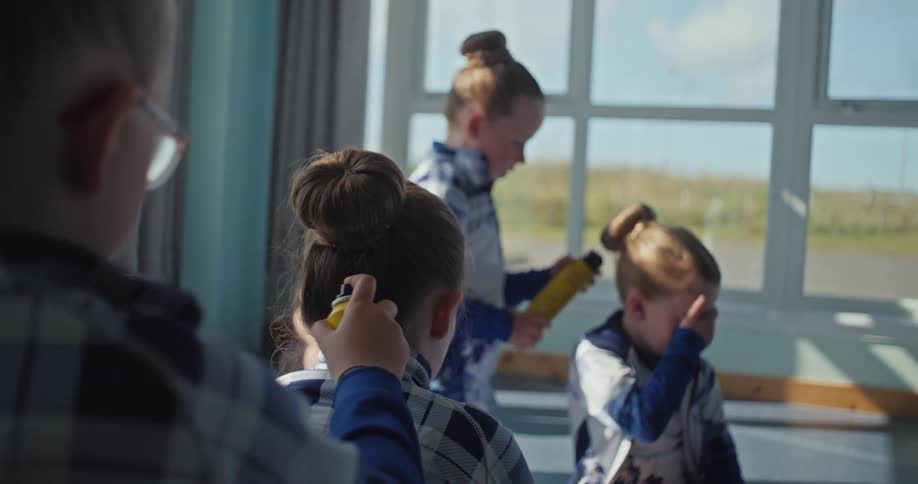 A group of four young girls with their hair in buns spraying hairspray on each others hair