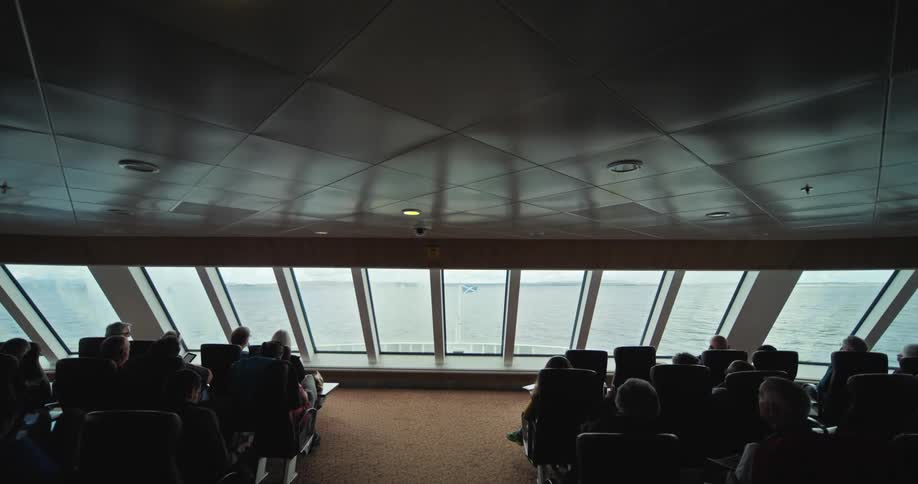 People sitting in armchairs on a boat moving through the sea