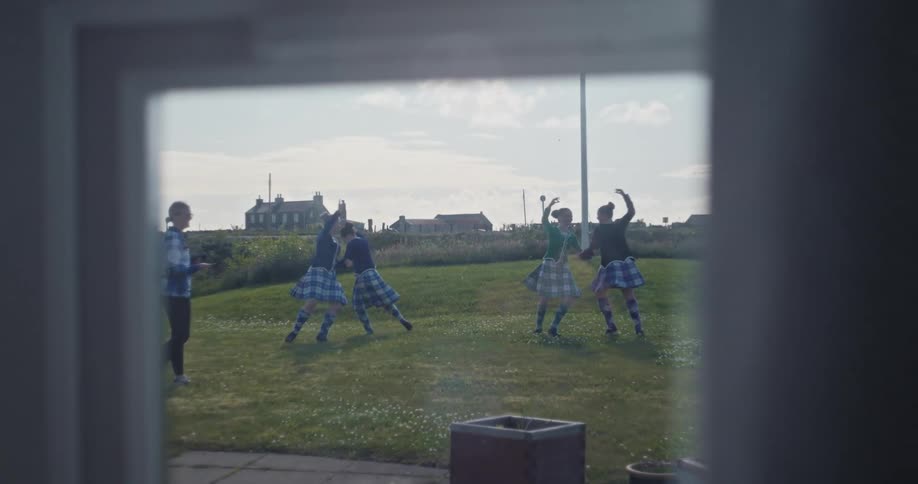 Through the window teenagers are dancing in pairs