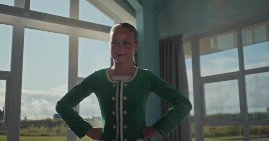 Girl in a green dance outfit posing in a sunlit room