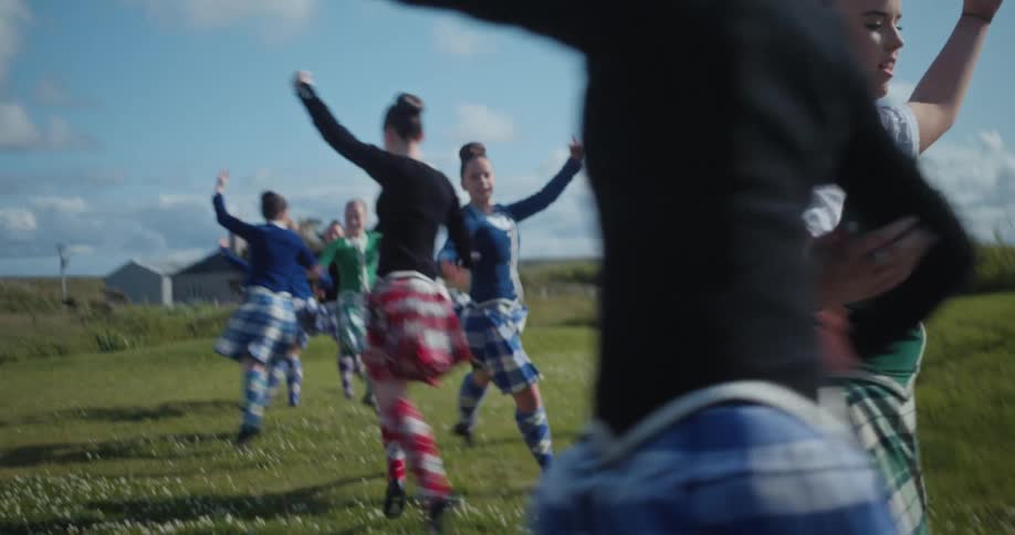 Couple of teenagers dancing in pairs on a grassland at midday