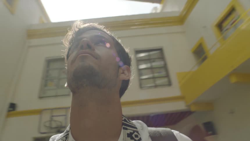 A man stands near a building looking up at the sky