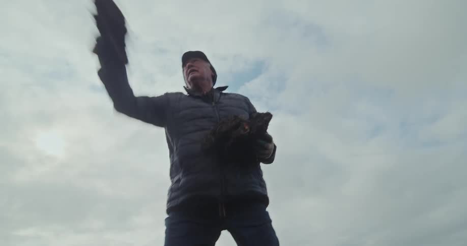 Elderly man in a field throwing dirt blocks