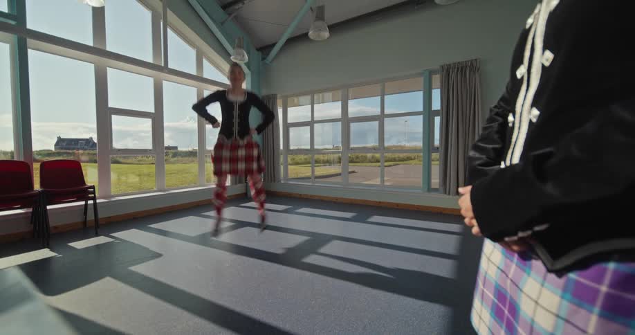 The girl is doing an irish dance by the window
