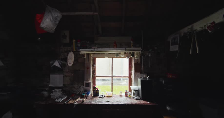 Dark garage with a window letting in daylight the space filled with various tools