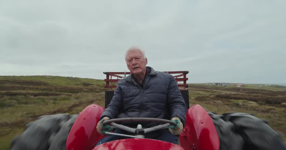 The man drives a red tractor on the farm