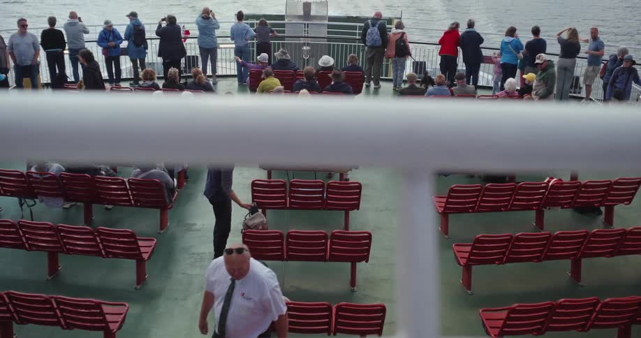 Passengers on a ferry watching the sea while others rest on the seats