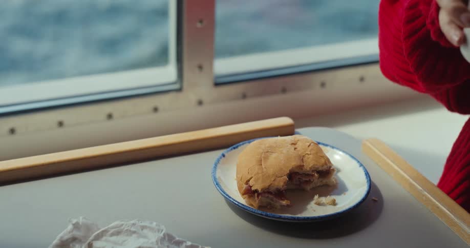 The person grabs their mug and drinks on the boat