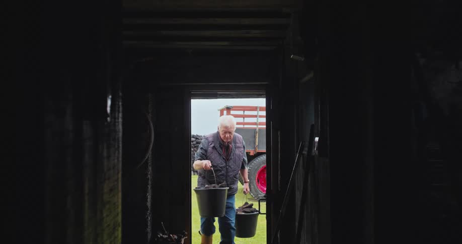 The farmer carries buckets in the barn