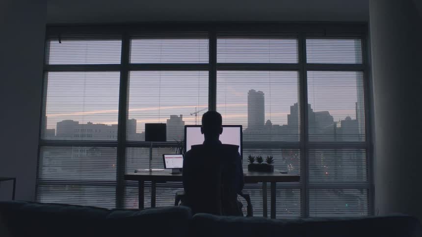 A man is sitting at a computer in his home