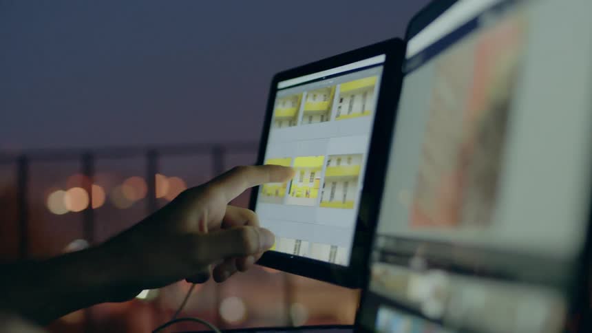 Person taps a computer monitor with desk overlooking a city