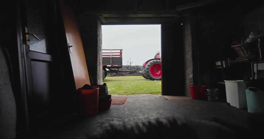 Tractor passing in front of a shed