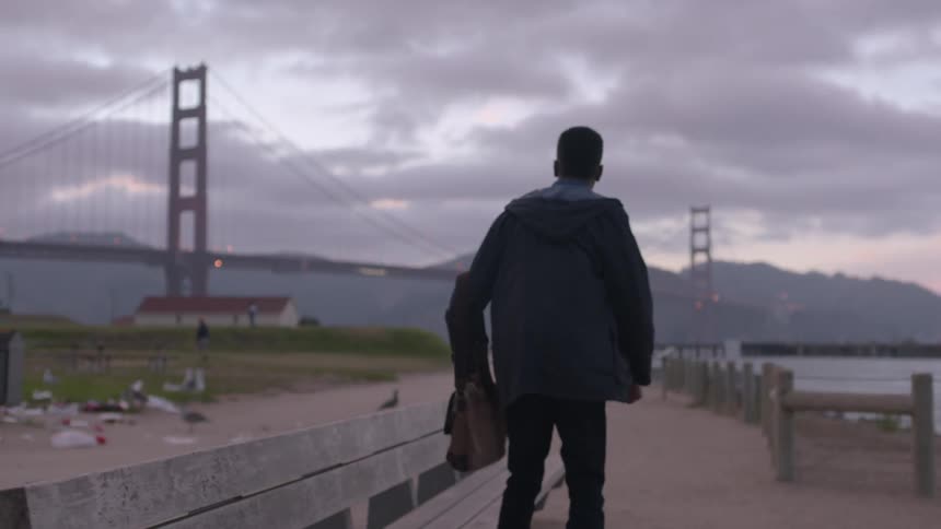 A man walks and sits down on a bench