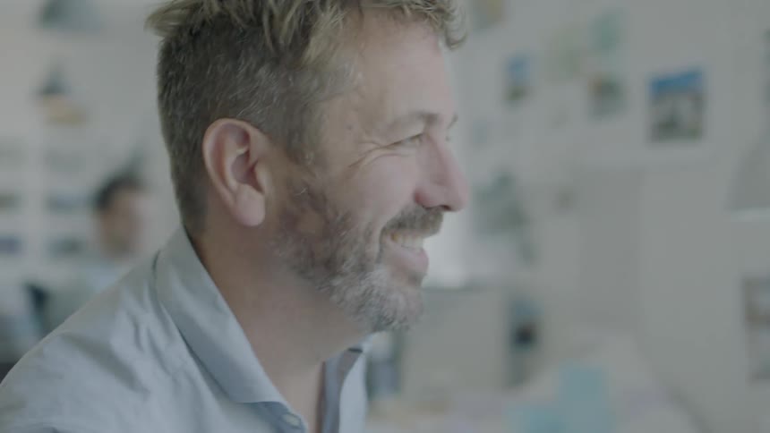 A man talks to co-workers in an office