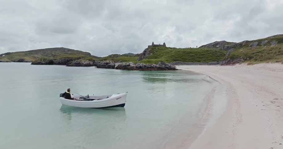 The man sits in the small boat on the beach