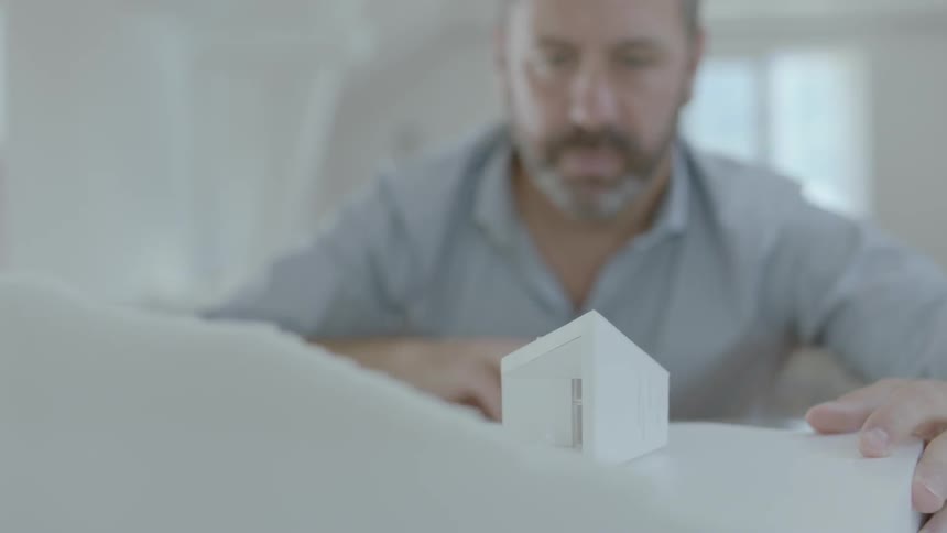 Man sitting at a desk examines a model building