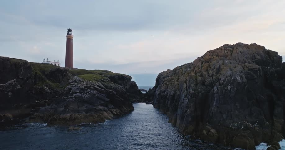 A coastal rock formation divided in two with a lighthouse on one side