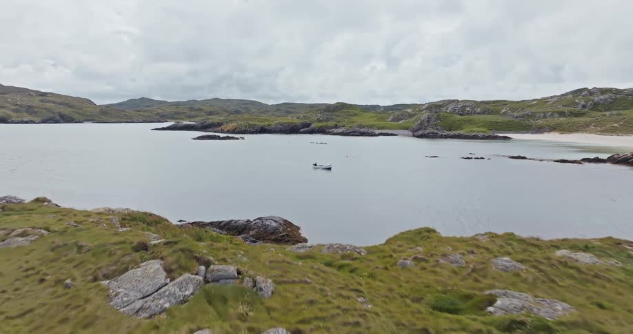 An aerial shot shows a small boat on a body of water with rocky land on all sides