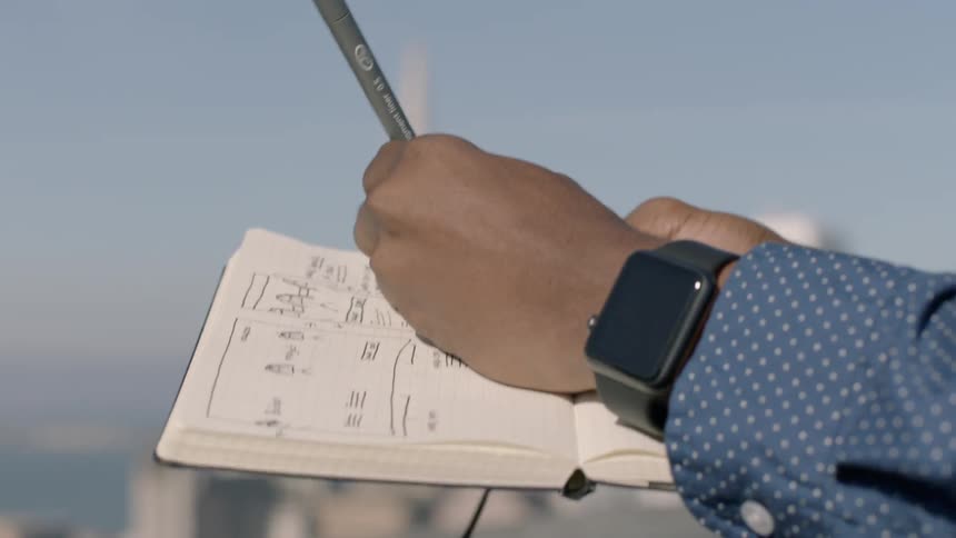 A person is writing in a notebook on a roof