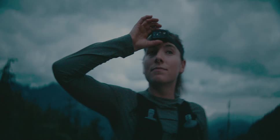 A persons face looks up towards the sky with a hand over the forehead headlamp