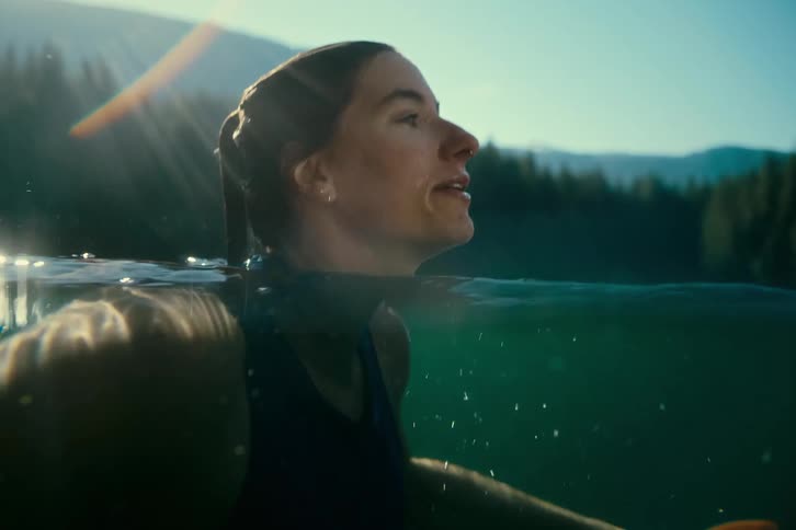 A persons head emerges from the water creating splashes and bubbles on the surface