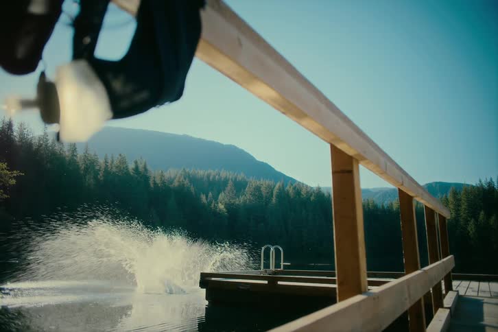 A young woman runs across a dock and leaps into a body of water creating a large splash