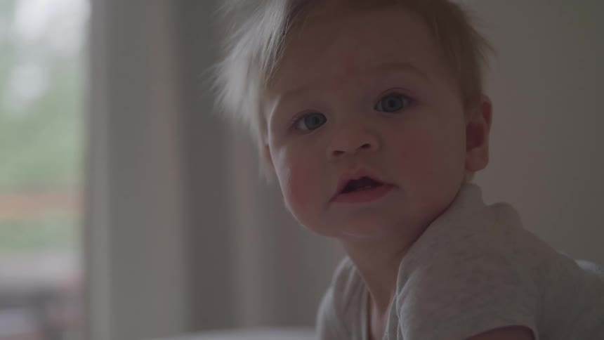 The baby is sitting on a bed