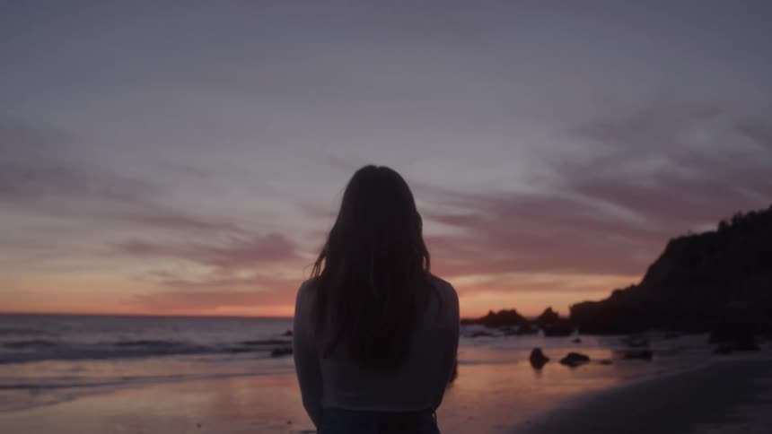Woman enjoying the scenery at the end of the afternoon on a beach