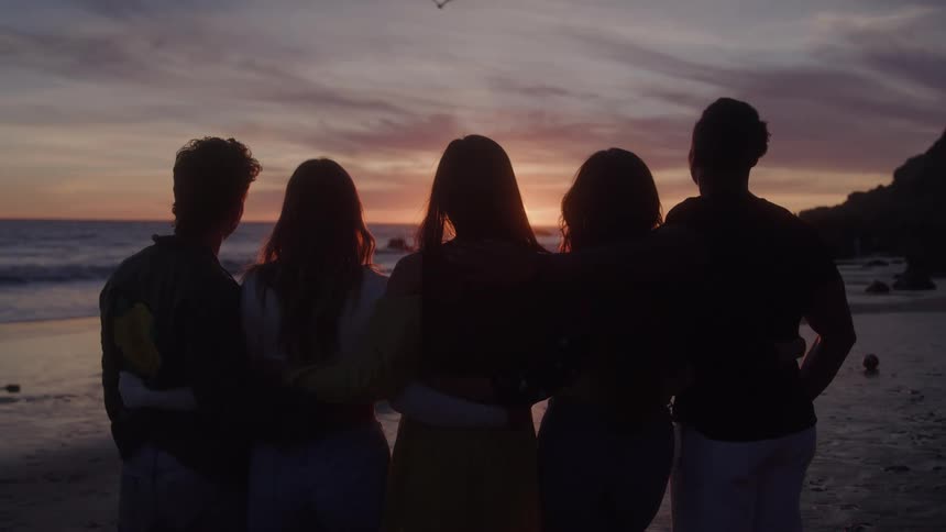 Small group of friends hugging at the end of the afternoon on the beach