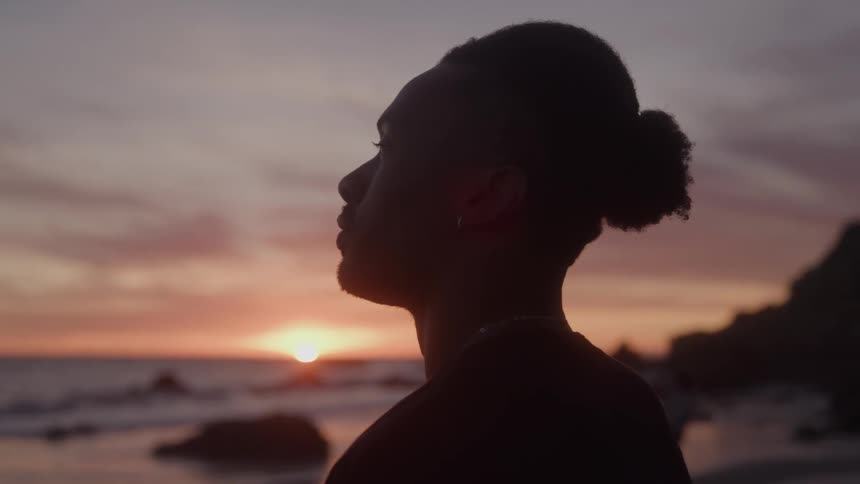 The silhouette of a persons head and neck is visible against a bright sunset